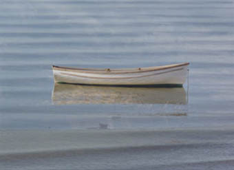 A white dory resting on glassy water at first light