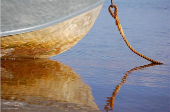 The golden hull of a boat reflected in still water