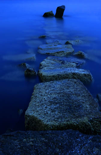 The breakwater at blue hour reaching into a darkening bay