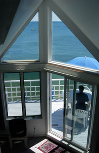 Inside a Watermark Inn suite — a peaked, windowed wall framing the bay and a private deck